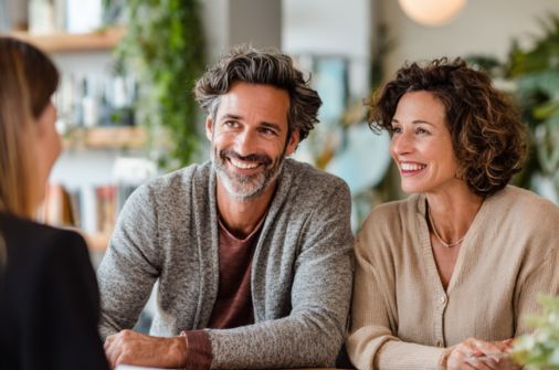 Parent representation lawyer meeting with two parents in a warm, modern office as they smile and discuss their case.